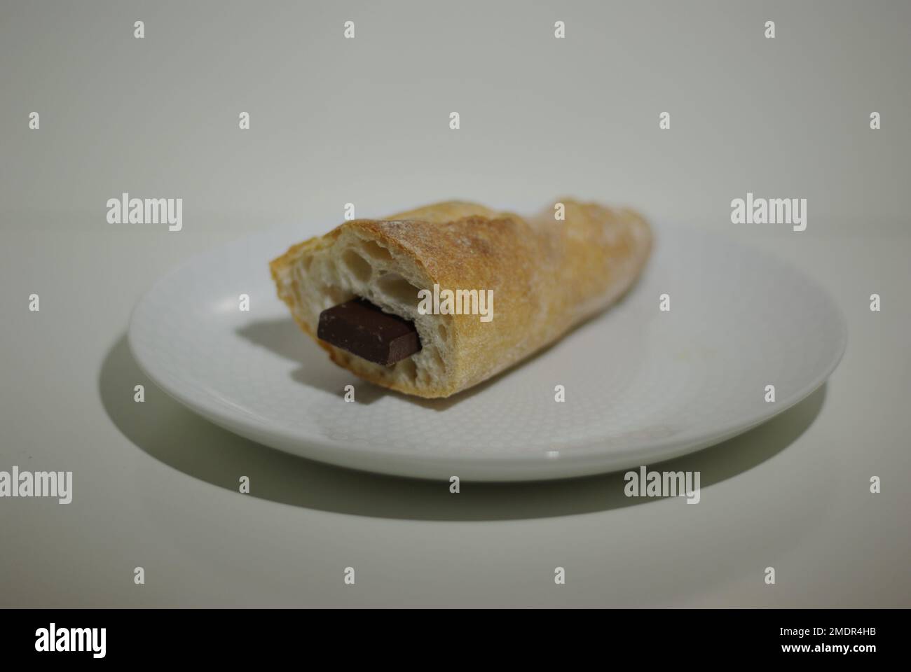 Baguette di pane con barretta di cioccolato su un piatto bianco Foto Stock