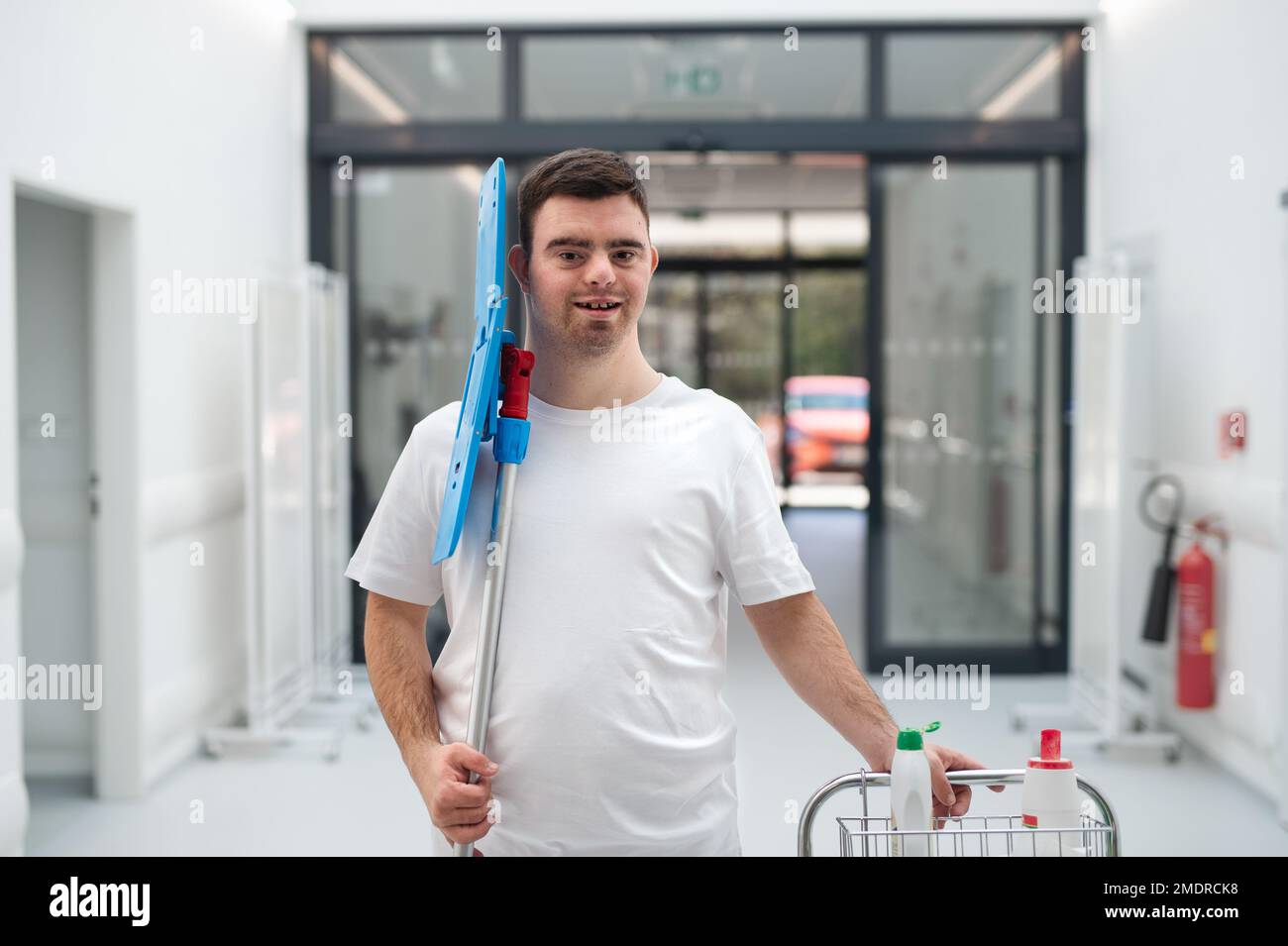Giovane uomo con sindrome di Down che lavora in un ospedale come più pulito. Concetto di integrazione di persone con disabilità nella società. Foto Stock