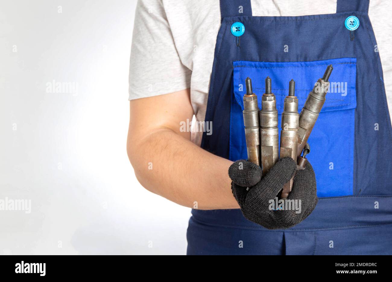 Il meccanico dell'automobile tiene gli iniettori dell'automobile del combustibile nella sua mano. Il concetto di sostituzione e messa a punto dell'impianto di alimentazione di un'auto presso un servizio di assistenza. Primo piano. Spazio di copia Foto Stock