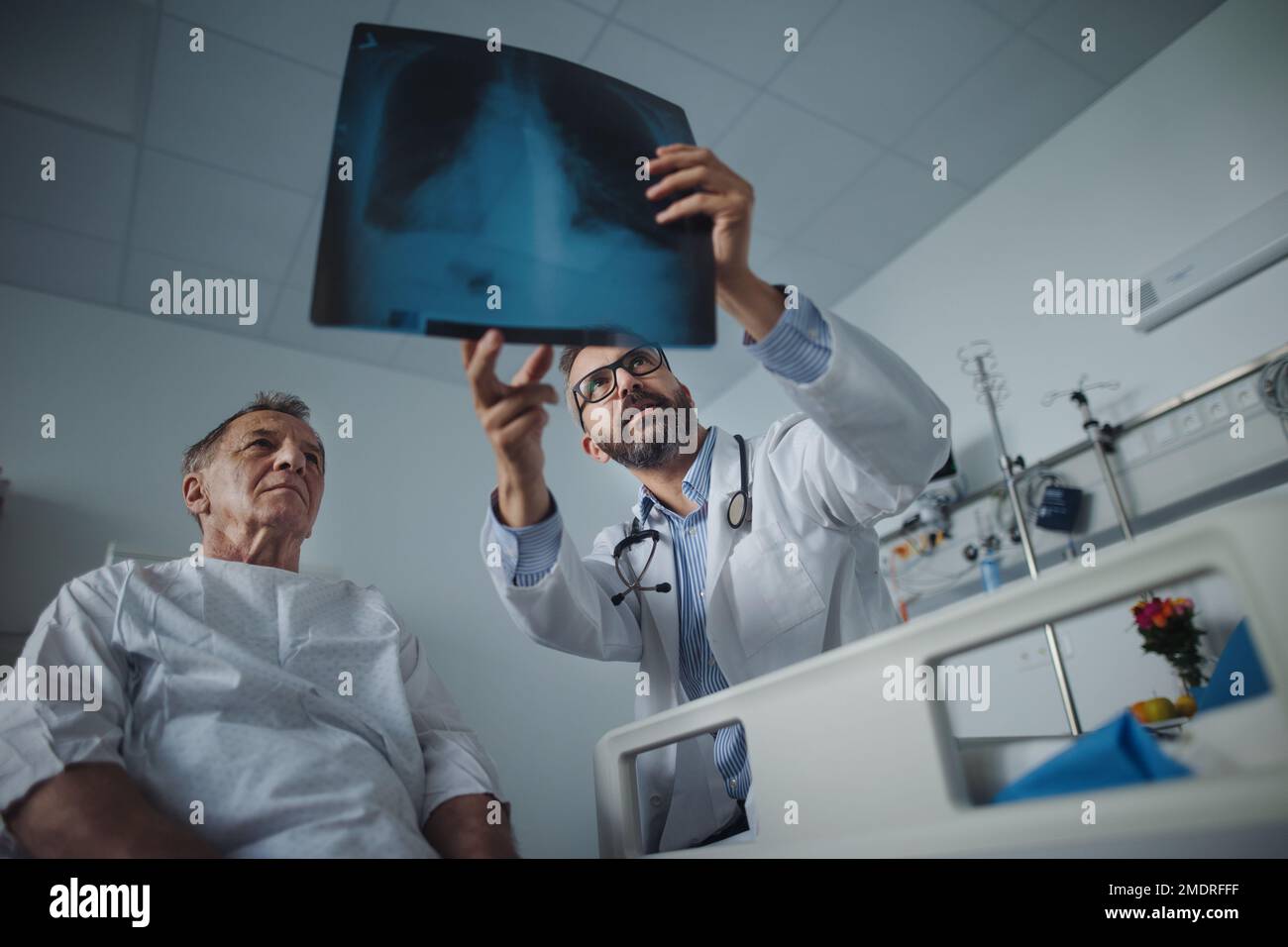 Medico maturo che mostra l'immagine radiografica dei polmoni del paziente anziano. Foto Stock