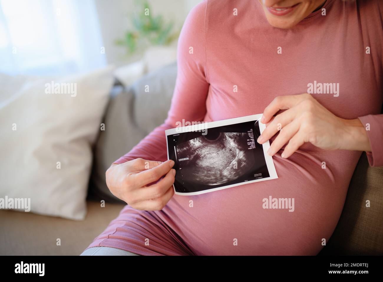 Donna incinta che mostra una foto ecografica del suo bambino. Foto Stock