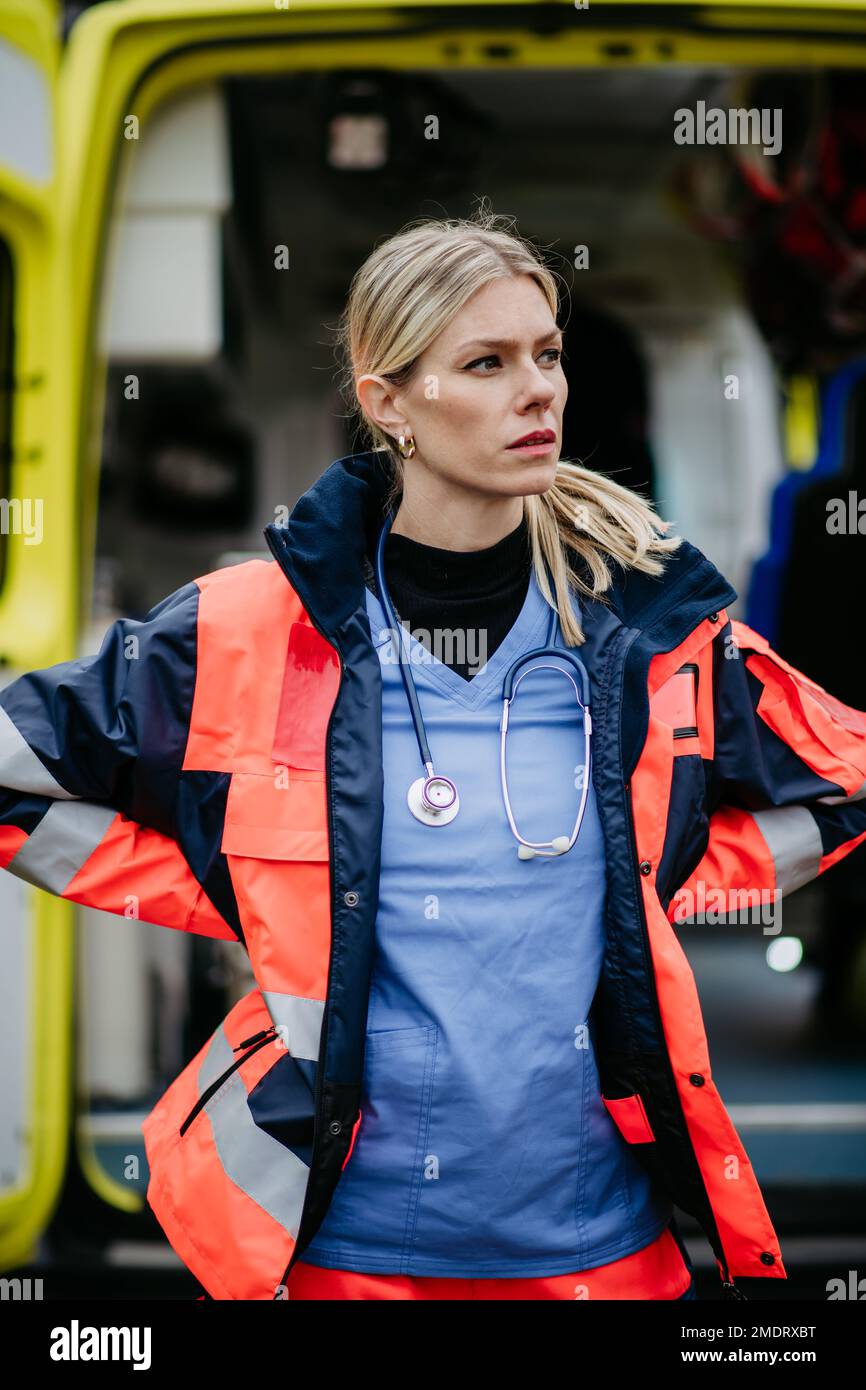 Ritratto di giovane donna medico in piedi di fronte alla macchina ambulanza. Foto Stock