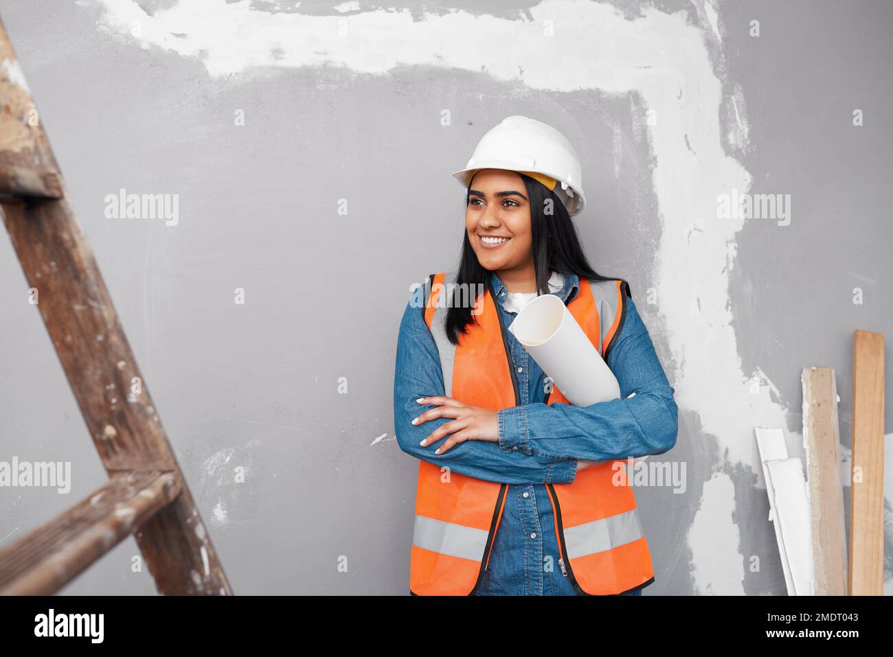Un attraente operaio di costruzione del sud asiatico tiene i programmi della costruzione sotto il suo braccio Foto Stock