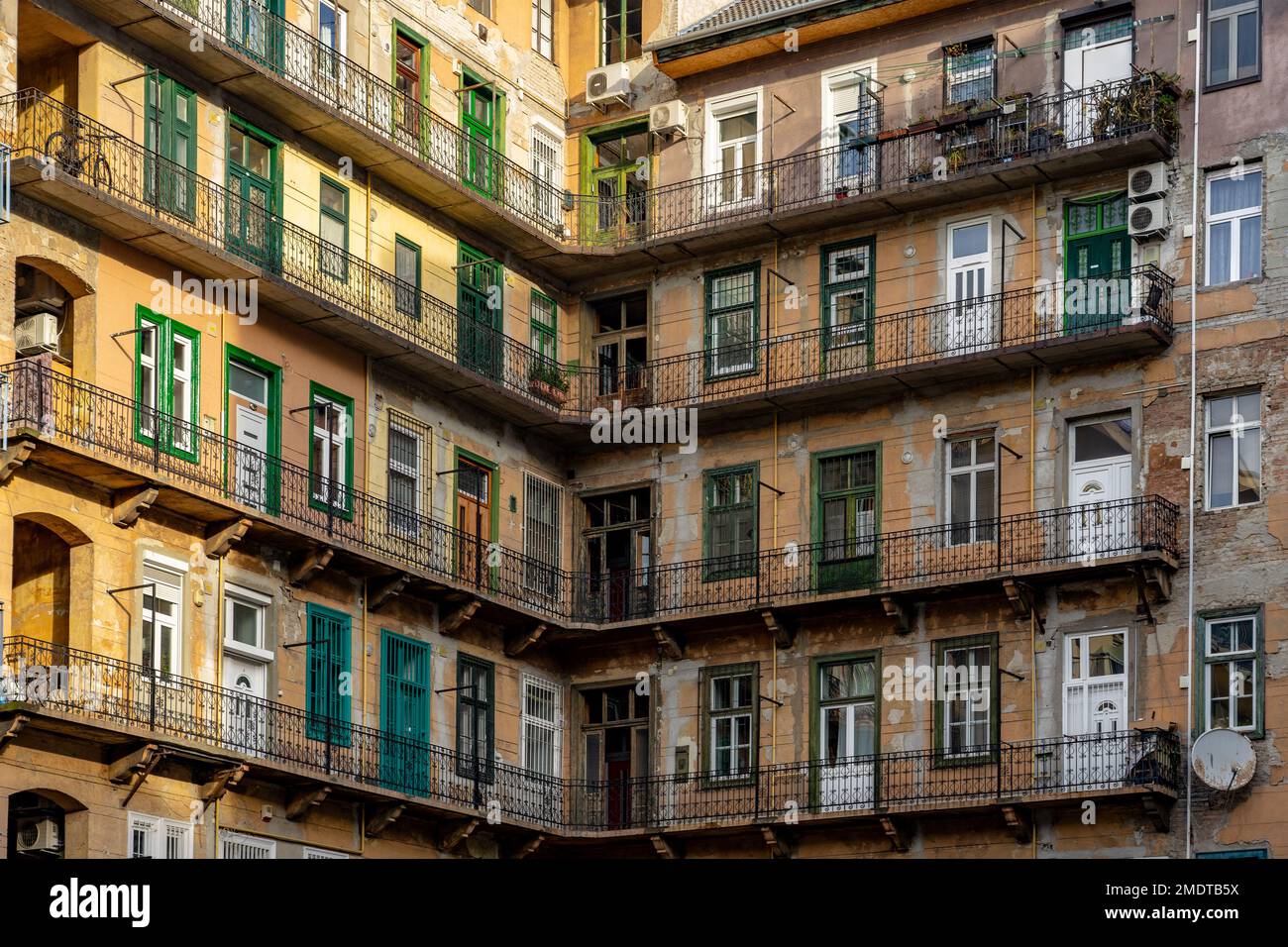Vecchio edificio tradizionale giallo residenziale a Budapest con gang e porte verdi. Foto Stock