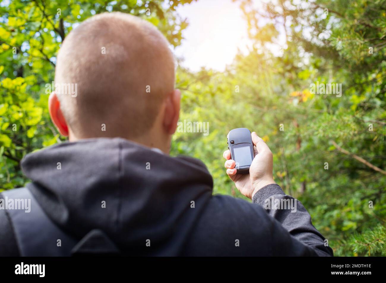 Un uomo con un navigatore nella foresta. Orientamento della posizione. Ricezione del segnale GPS, tecnologia. Copia spazio per il testo Foto Stock