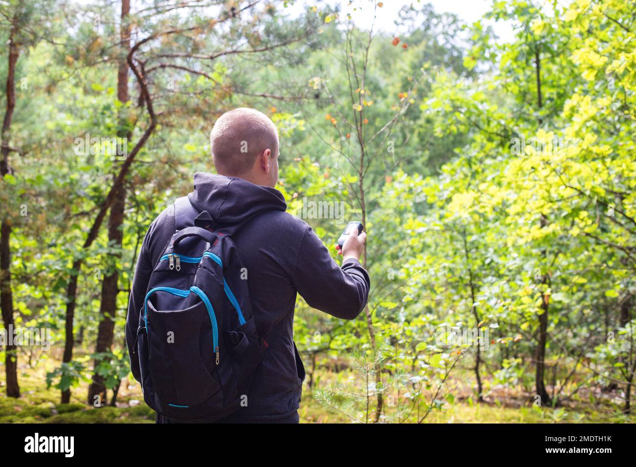 Un uomo con un navigatore nella foresta. Orientamento della posizione. Ricezione del segnale GPS, tecnologia. Foto Stock