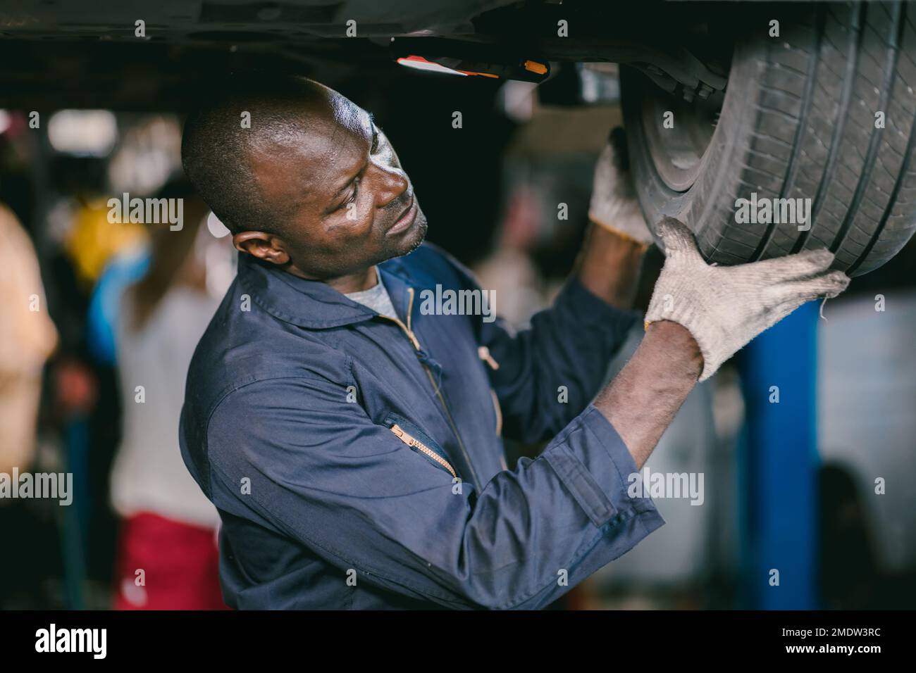 meccanico personale lavoratore maschio di controllo pneumatico auto sostituire vecchio pneumatico in auto garage servizio Foto Stock