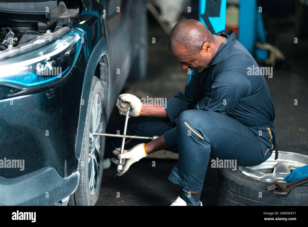 meccanico maschio personale di cambio sostituire pneumatico auto lavoro in garage auto manutenzione ruota anteriore Foto Stock