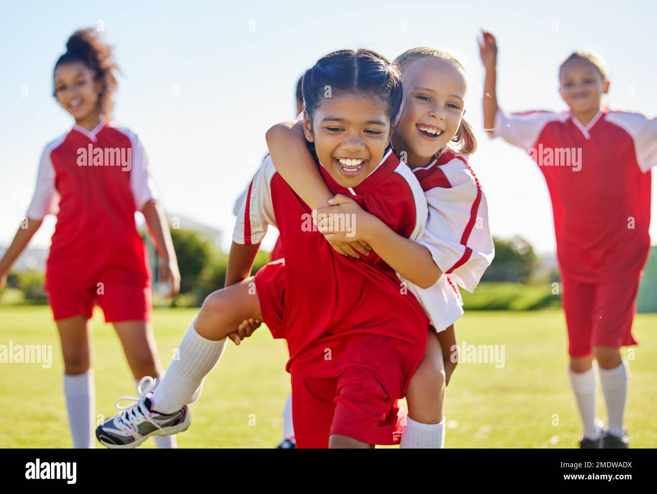 Calcio, festa della ragazza e campo con felice piggyback, squadra di sostegno alla costruzione e la solidarietà per vincere la partita. Bambini femminili, diversità sportiva e. Foto Stock