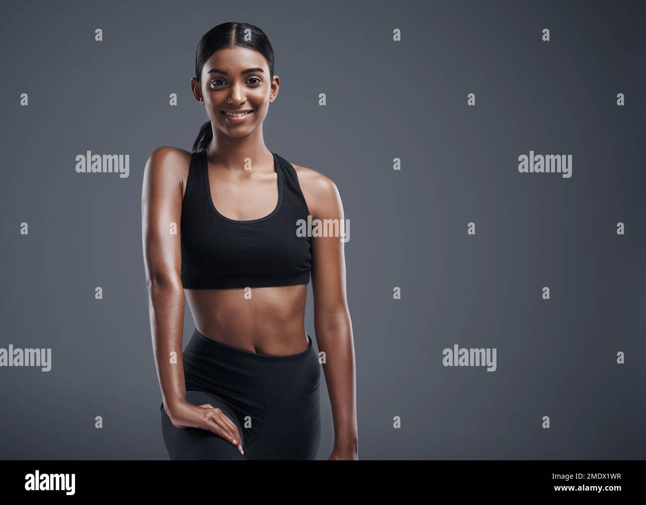 Il fitness mi dà questo tipo di bagliore. Studio ritratto di una giovane donna sportiva che posa su uno sfondo grigio. Foto Stock
