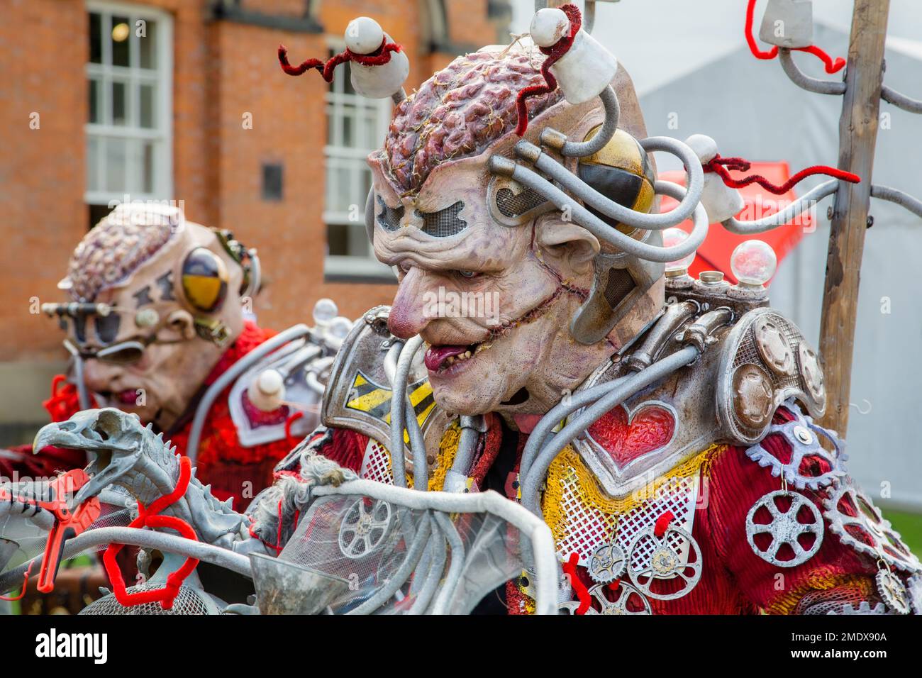 Primo piano di un personaggio alieno o mutante dall'aspetto spaventoso con il suo cervello che mostra e un volto scaraventato che indossa abiti futuristici. Foto Stock