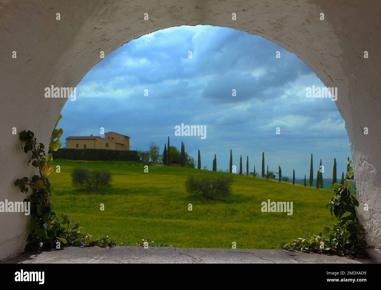 Arco di una finestra che si affaccia su una tipica collina toscana con un cielo di piombo e cipressi Foto Stock