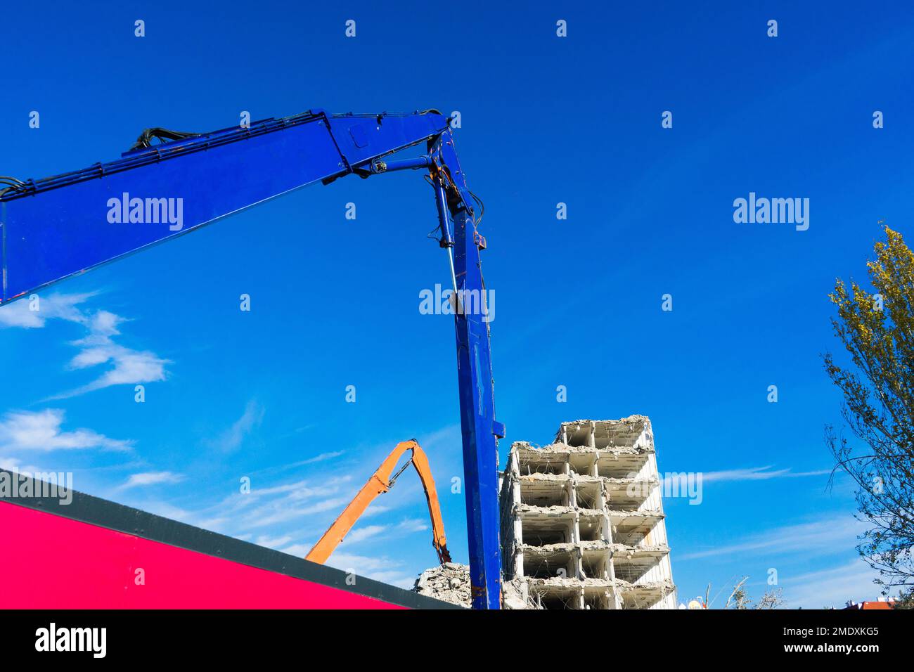 Demolizione del vecchio edificio con sloopkraan contro cielo nuvole blu. Foto Stock