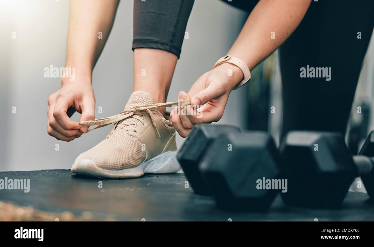 Fitness, mani o donna cravatta scarpe pizzo prima di iniziare l'esercizio manubri, palestra o allenamento sportivo. Salute, benessere e gambe di ragazza, atleta Foto Stock