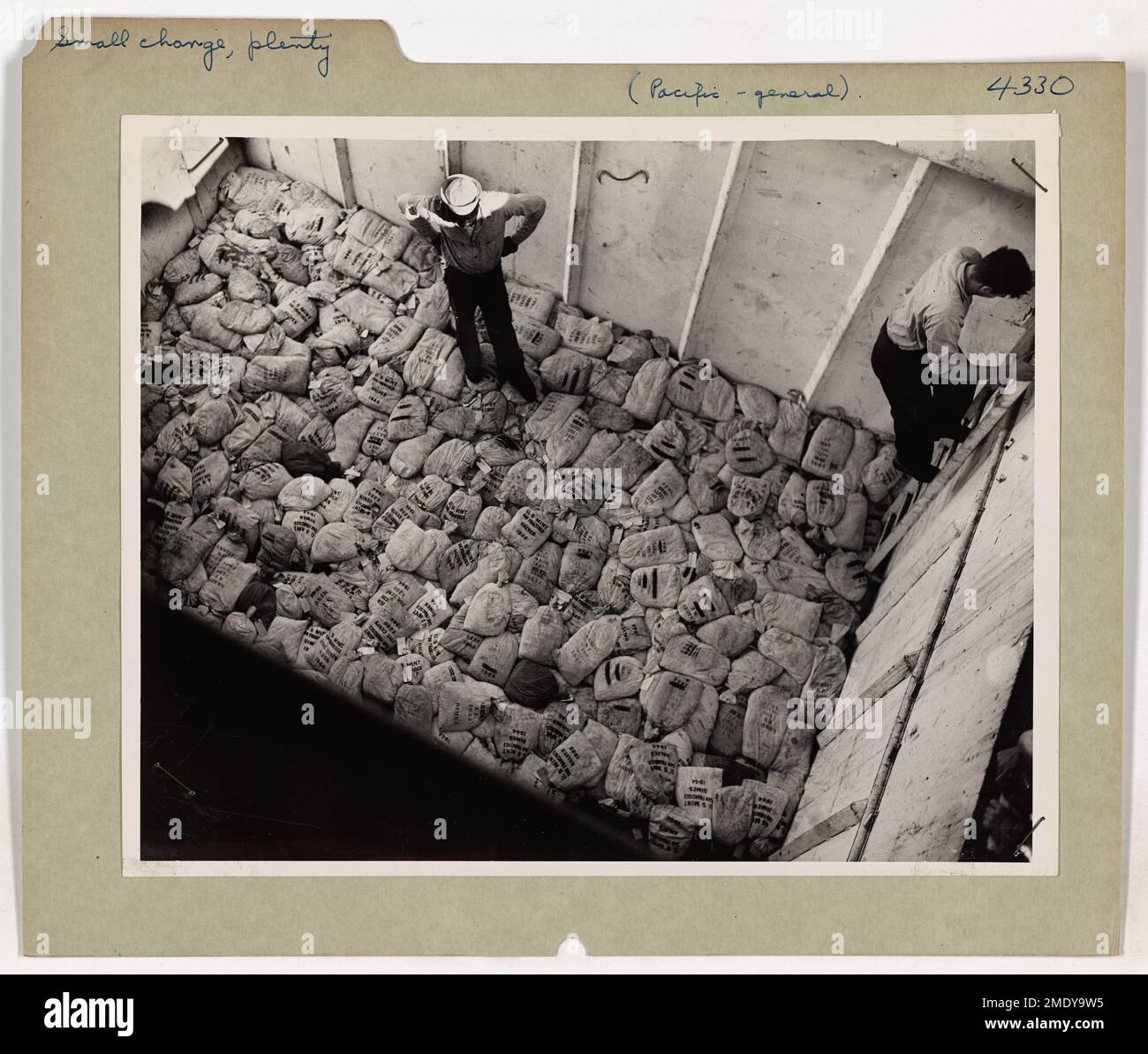 Un Navy Seabee scarica oltre un terzo di un milione di dollari in piccoli cambiamenti, inclusi penny, nichel e dii, in una base del Pacifico durante la seconda guerra mondiale per supportare le operazioni militari. Foto Stock