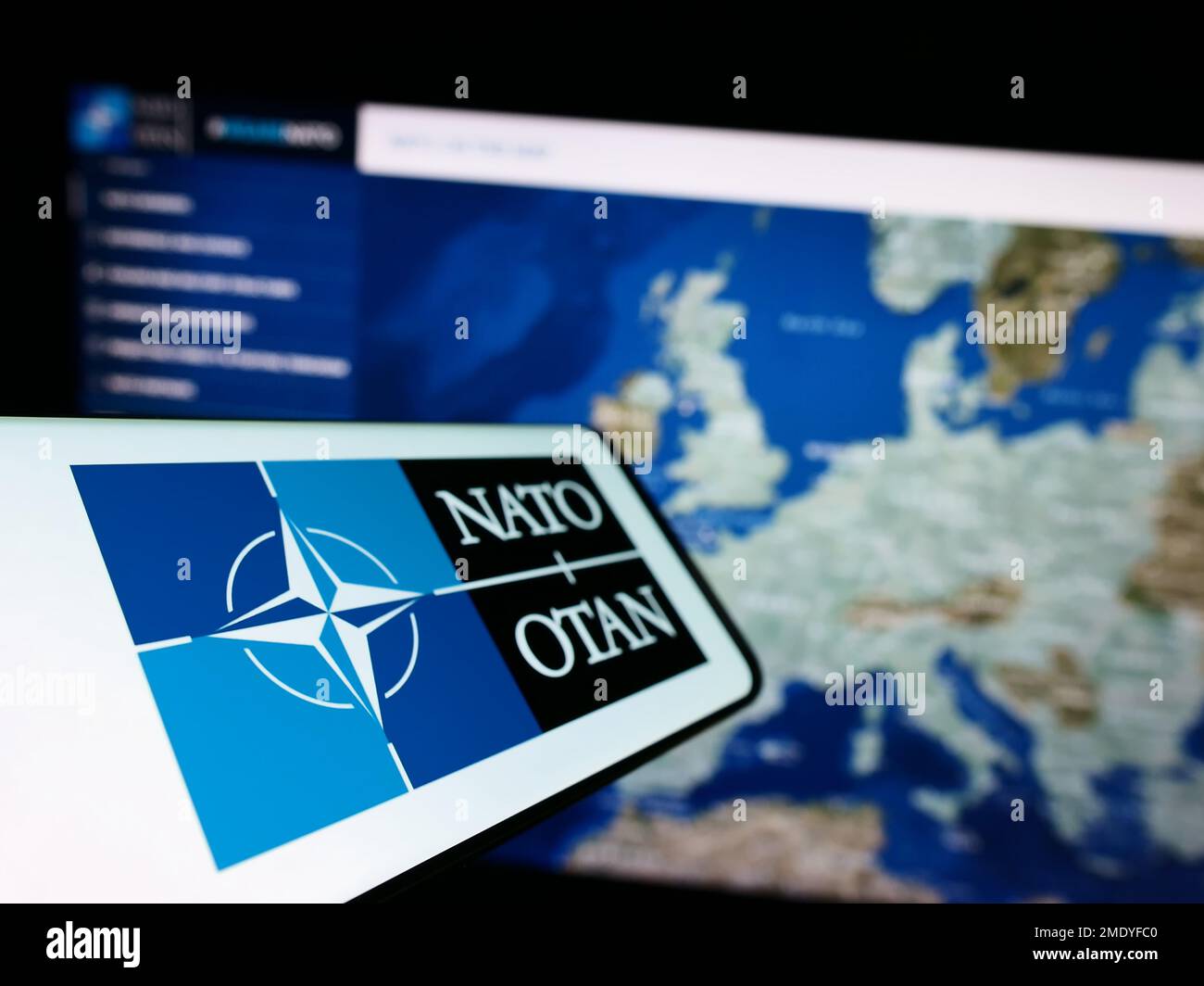 Smartphone con logo della NATO (North Atlantic Treaty Organization) sullo schermo di fronte al sito Web. Messa a fuoco a sinistra del display del telefono. Foto Stock