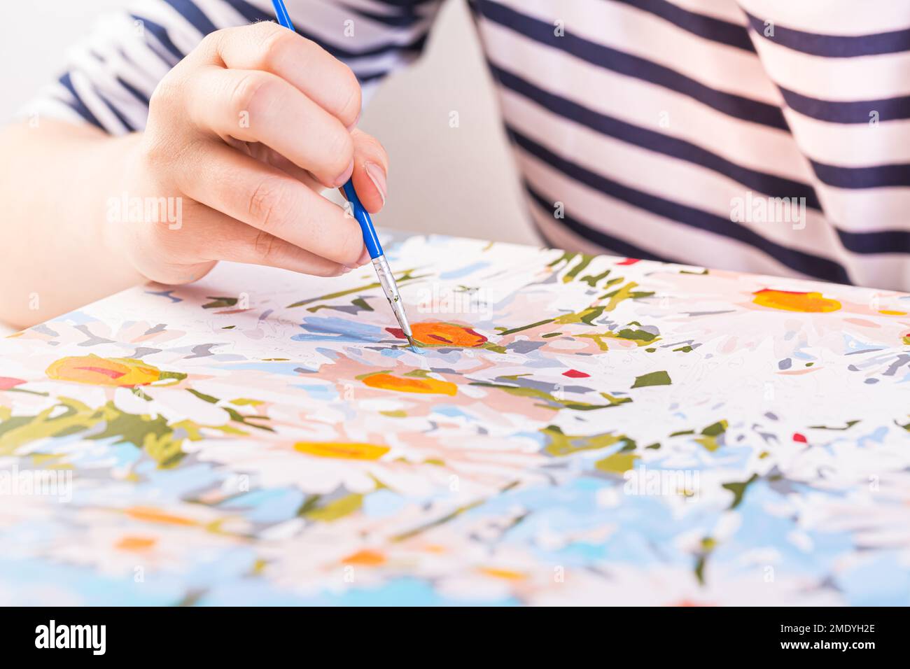 Una mano con disegno a pennello di fiori con pitture acriliche su tela. Concetto di arte. Foto Stock