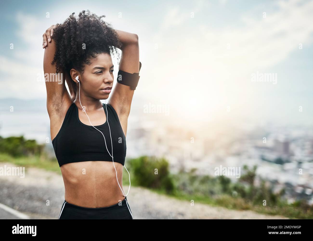 Allentando i suoi muscoli per un workout intenso. una giovane donna sportiva che allunga le braccia mentre si esercita all'aperto. Foto Stock