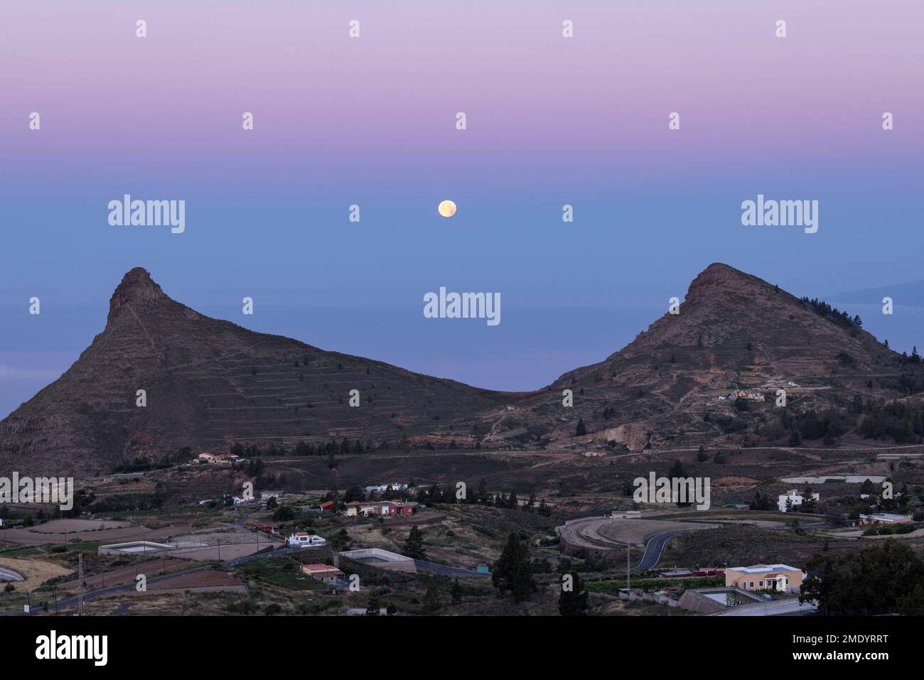 Vista sul villaggio di Ifonche alle località costiere di Los Cristianos e Las Americas all'alba con la luna piena impostazione a ovest, Adeje, Tene Foto Stock
