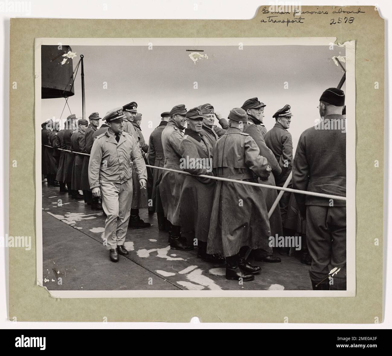 Prigionieri tedeschi a bordo di una Guardia Costiera con equipaggio di trasporto. Essere prigioniero alleato non sembra essere una cosa sgradevole per un soldato tedesco in questi giorni. Questi ufficiali nazisti e arruolarono uomini, catturati in Francia, ridono e scherzano tra loro mentre costeggiano la ferrovia di un trasporto con equipaggio della Guardia Costiera portandoli alla sicurezza di un campo di internamento negli Stati Uniti. Guardia costiera di Lieut. (j.g.) R.J. Campbell, Jr., 2619 St Mary's Avenue, Hannibal, Missouri, li tiene d'occhio. Foto Stock