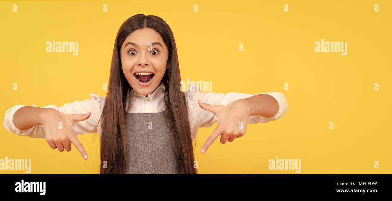 felice ragazza punto dito su bianco foglio di carta rosa per la copia spazio, promozione. Faccia del bambino, manifesto orizzontale, ritratto isolato della ragazza adolescente Foto Stock