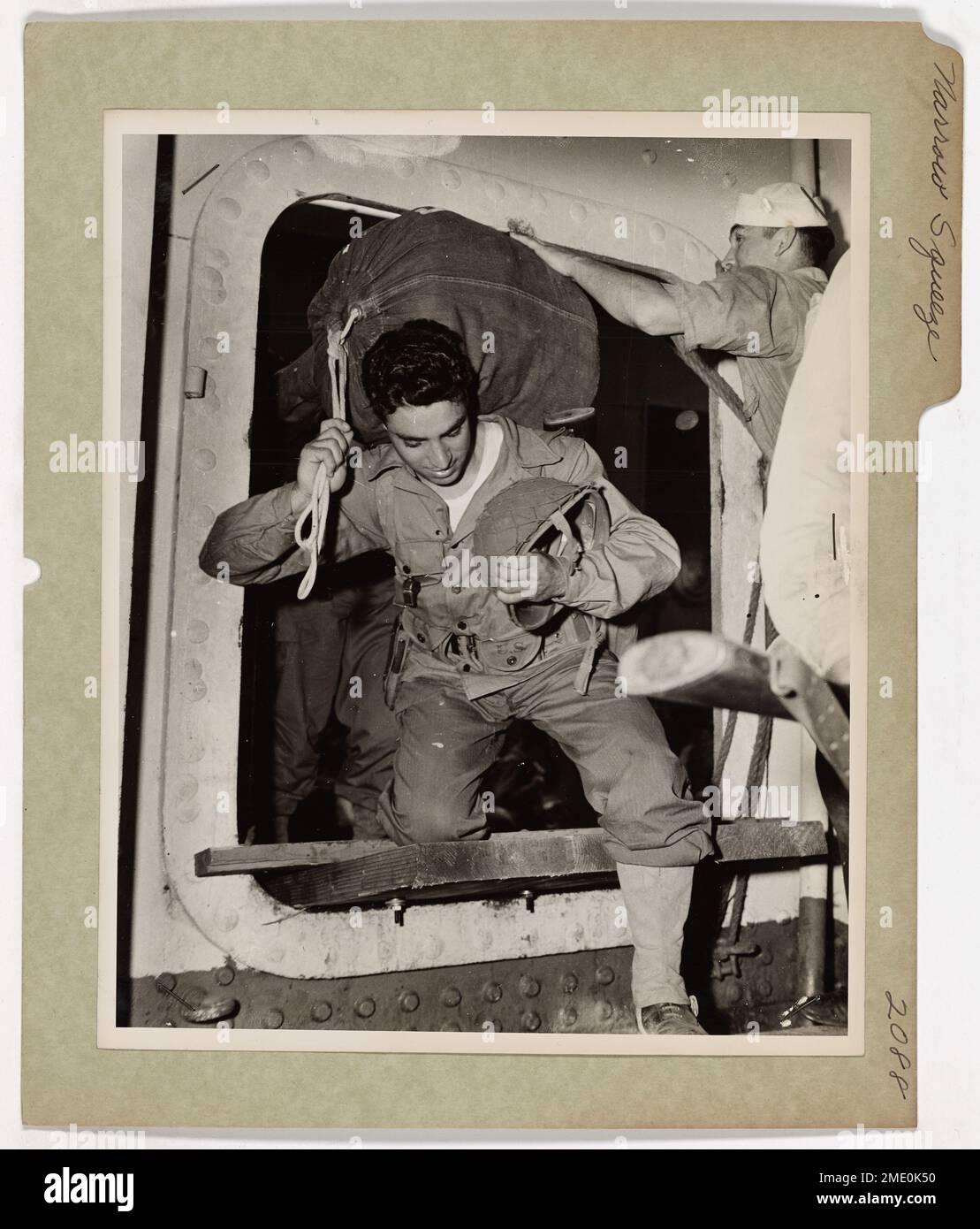 Un guardiano della costa rassicura un Marine mentre si imbarca su un trasporto di combattimento con equipaggio della Guardia Costiera in un porto del Pacifico meridionale. La nave si dirige verso un fronte di guerra, sottolineando gli stretti quartieri del trasporto in tempo di guerra. Foto Stock