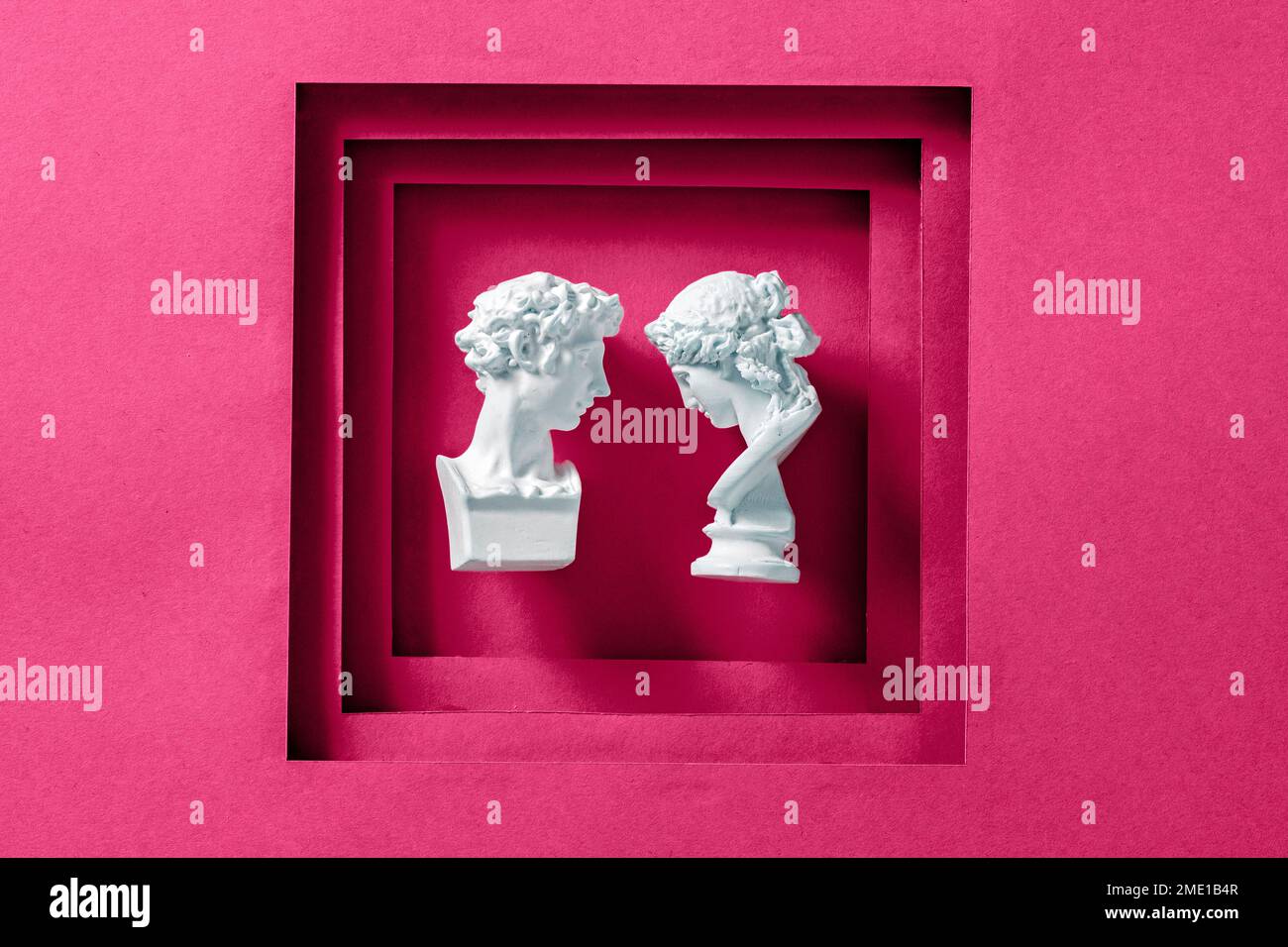 Due statue antiche come una giovane coppia romantica incorniciata con uno sfondo magenta come un concetto minimo di amore, felicità e matrimonio. Foto di alta qualità Foto Stock