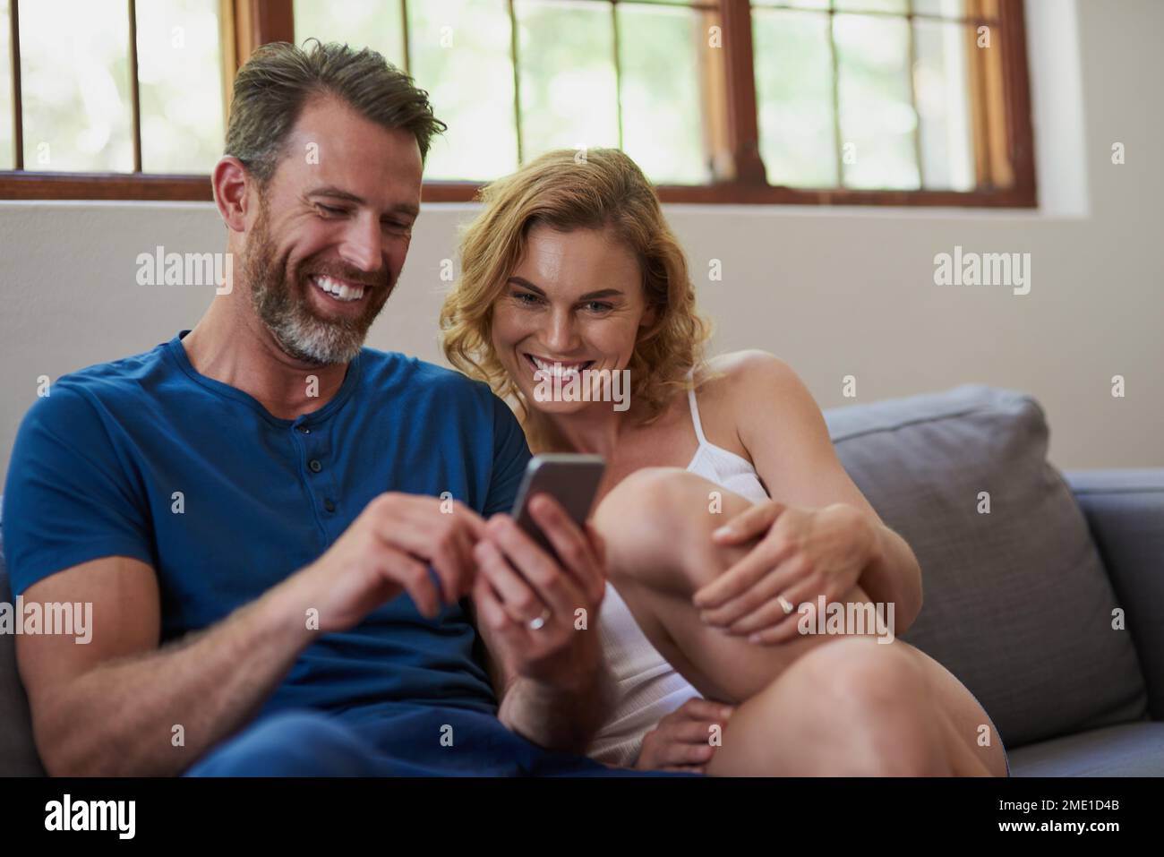 Le coppie felici condividono i momenti felici. una felice coppia di mezza età che utilizza un telefono cellulare insieme sul divano a casa. Foto Stock