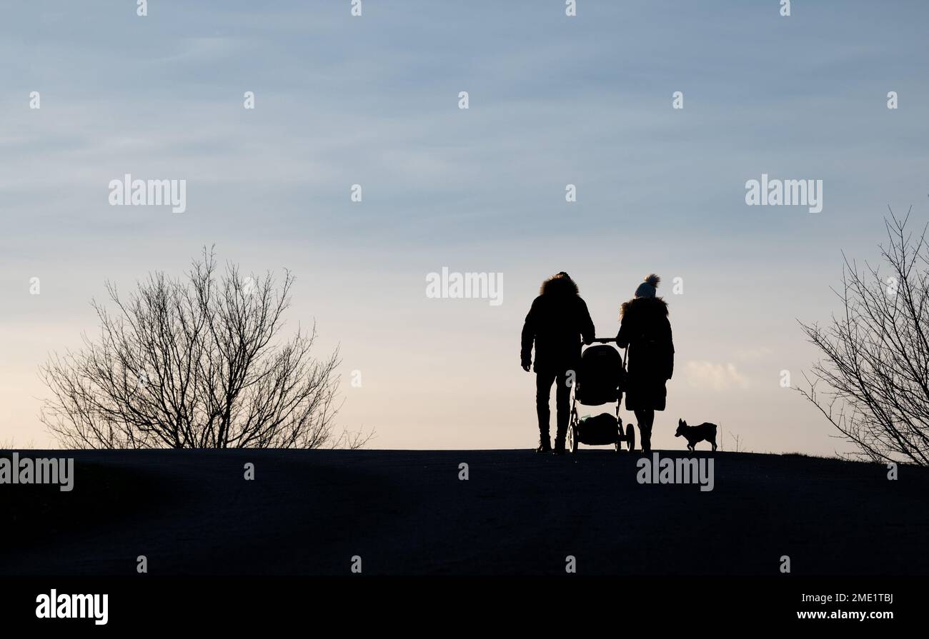 Genitori con un passeggino in una passeggiata fuori Foto Stock Genitori con un passeggino in una passeggiata fuori Foto Stock