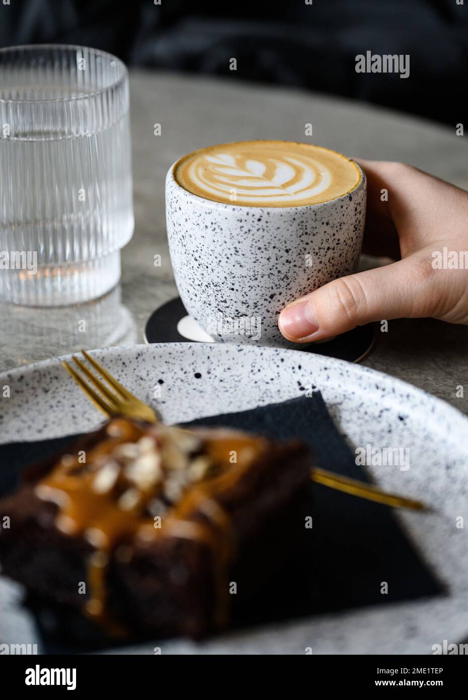 Mano che tiene un cappuccino su un tavolo Foto Stock
