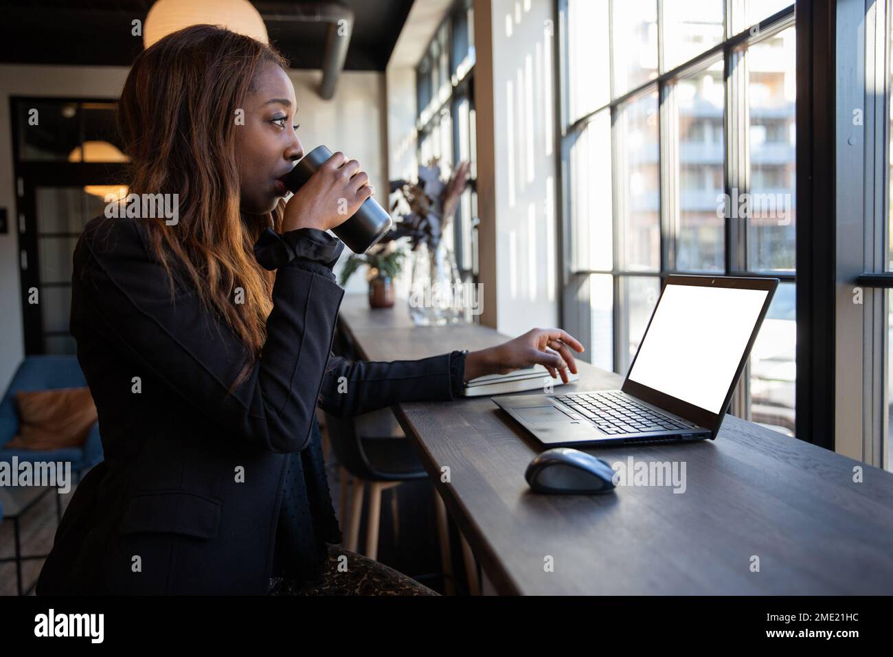 Il lavoratore bianco del collare beve il caffè in ufficio, schermo bianco del laptop con mockup Foto Stock