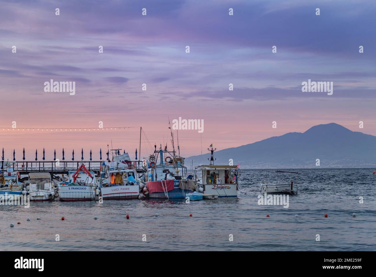 Barche ormeggiate a Marina Grande al tramonto, con il Vesuvio in lontananza, Sorrento, Campania, Italia. Foto Stock