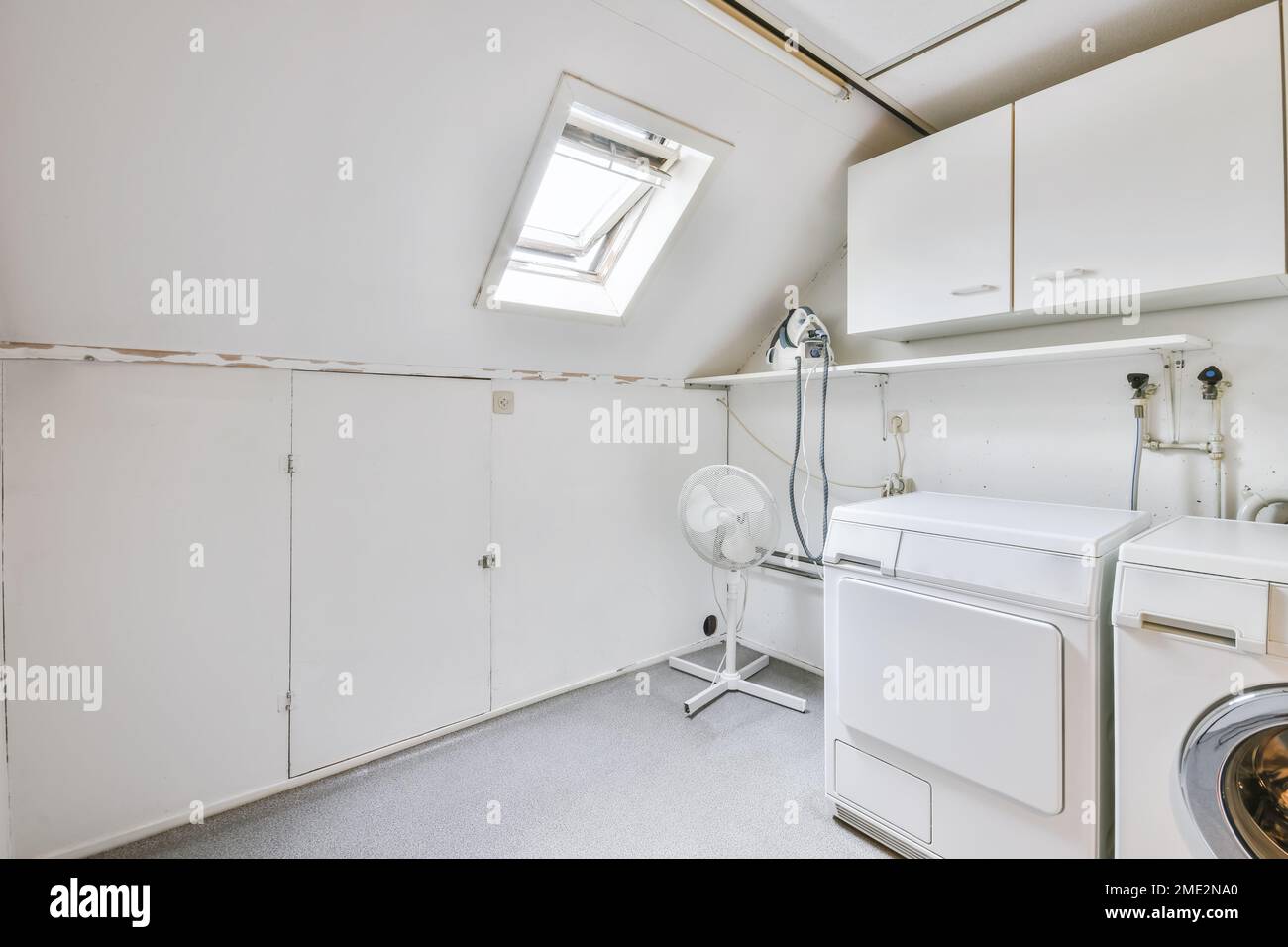 Interno di una moderna e luminosa lavanderia con lavatrice e asciugatrice,  ventilatore e armadi Foto stock - Alamy
