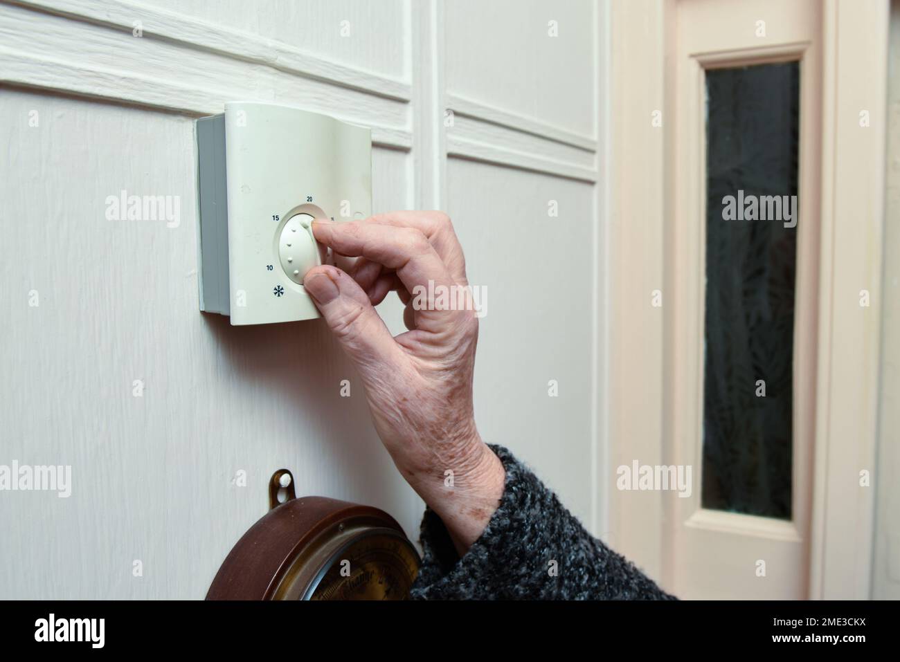 Donna matura abbassa il riscaldamento centrale a casa per risparmiare denaro Foto Stock