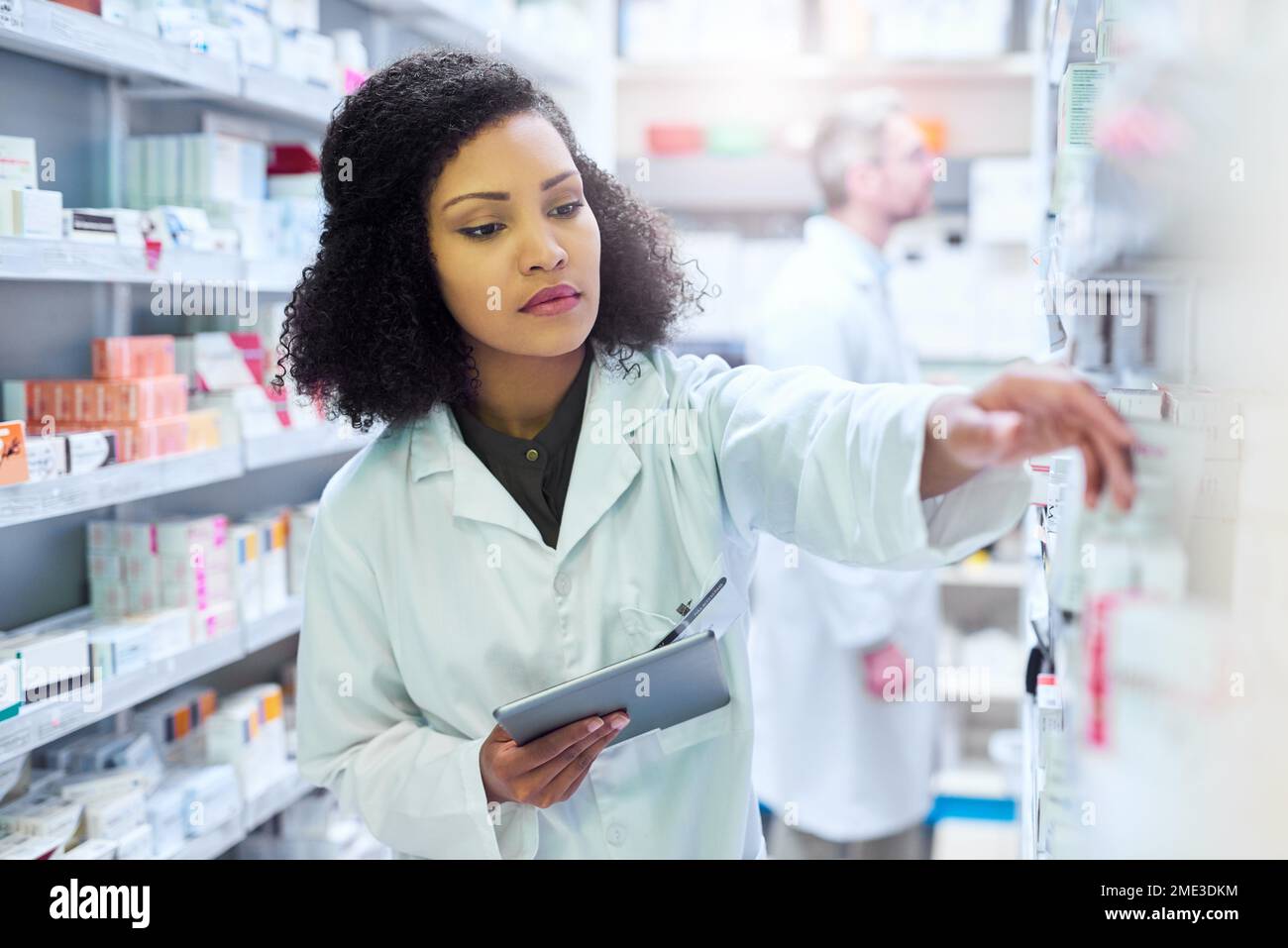 La gestione di una farmacia moderna richiede una tecnologia moderna. una giovane donna che usa un tablet digitale per fare l'inventario in una farmacia. Foto Stock