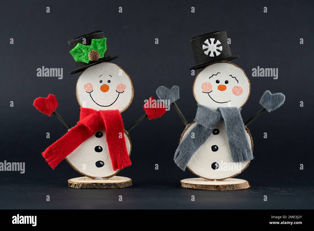 Pupazzo di neve fatto di fette di legno e decorato con dettagli invernali su sfondo nero Foto Stock