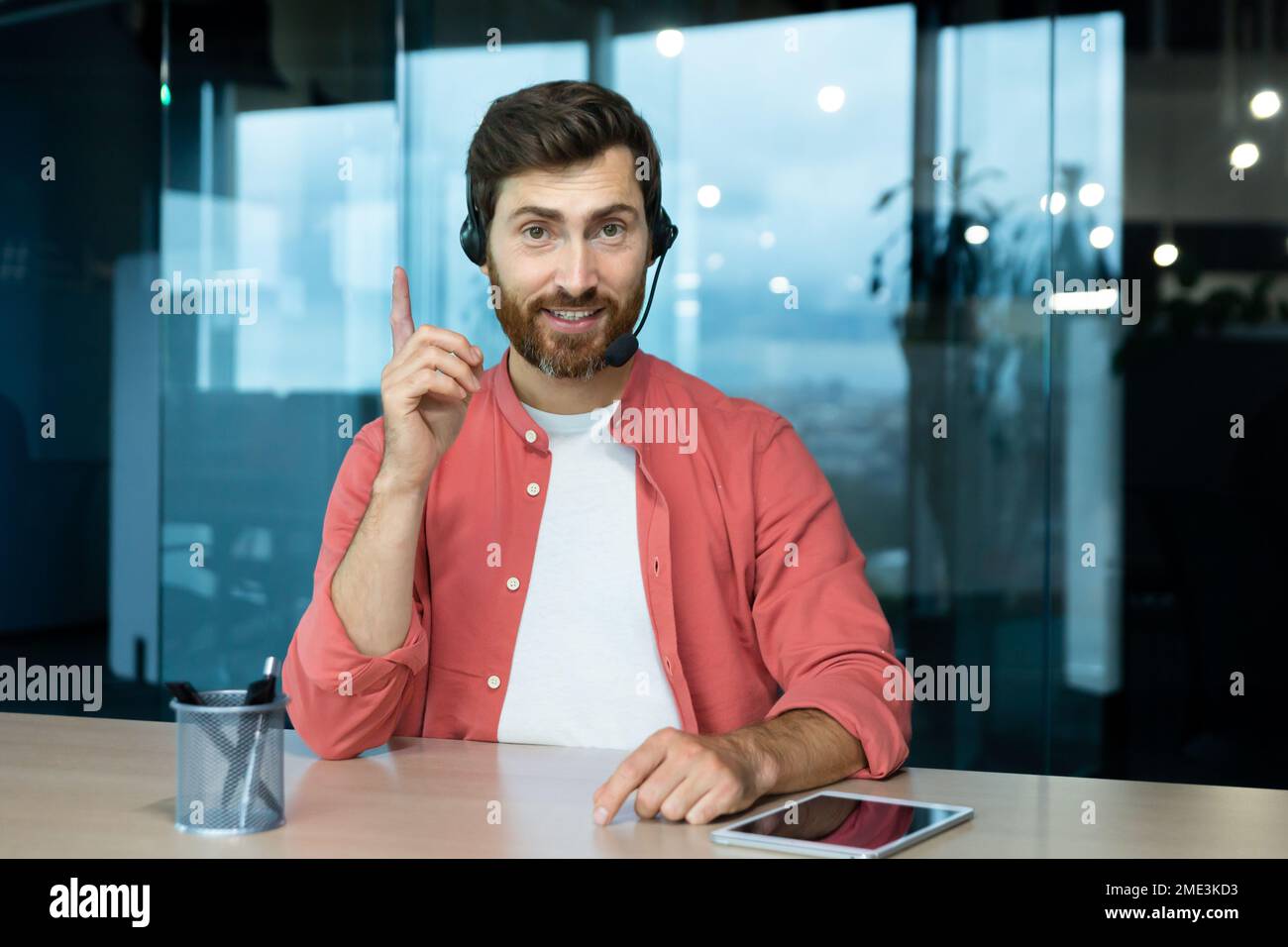 Webcam vista pov, uomo in ufficio con cuffie per videochiamate sorridente e guardando la fotocamera, venditore di affari online comunica con i clienti, lavora in remoto laptop a riunioni online colleghi Foto Stock