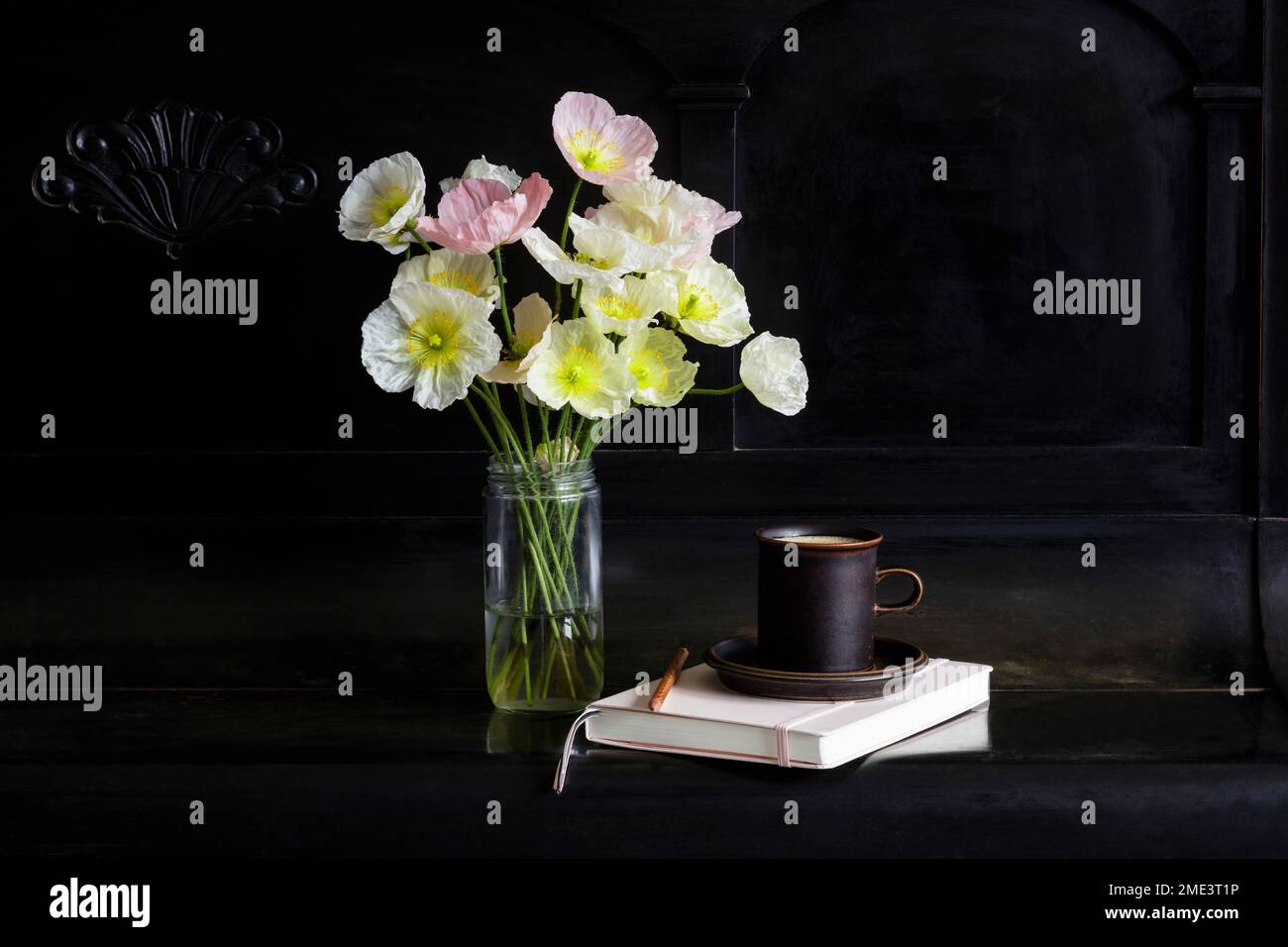Islanda fiori di papavero in vaso di vetro da caffè e diario su pianoforte nero Foto Stock