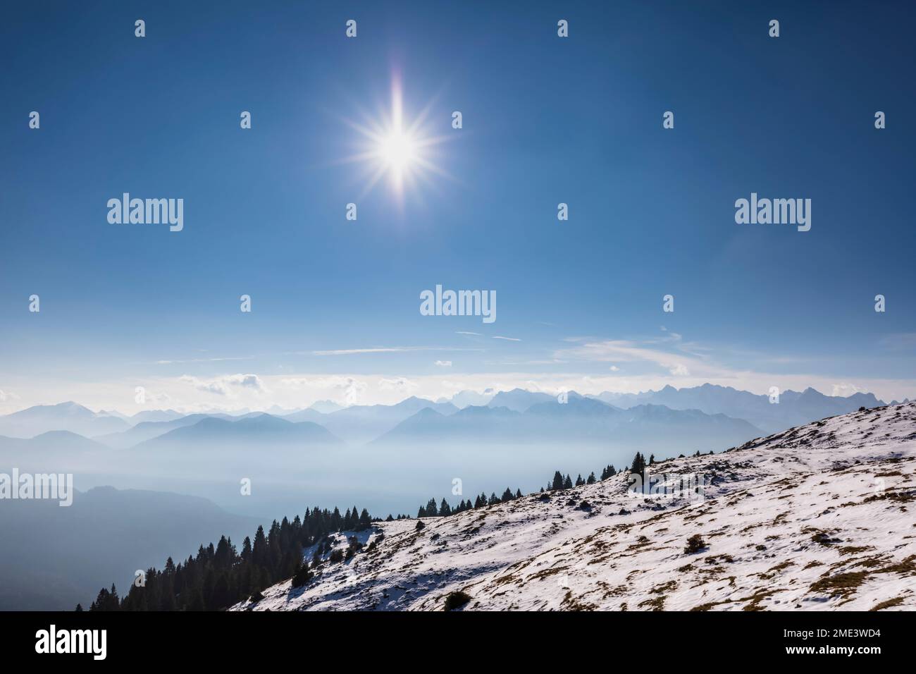 Germania, Baviera, sole che splende sulle montagne estere avvolte nella nebbia Foto Stock