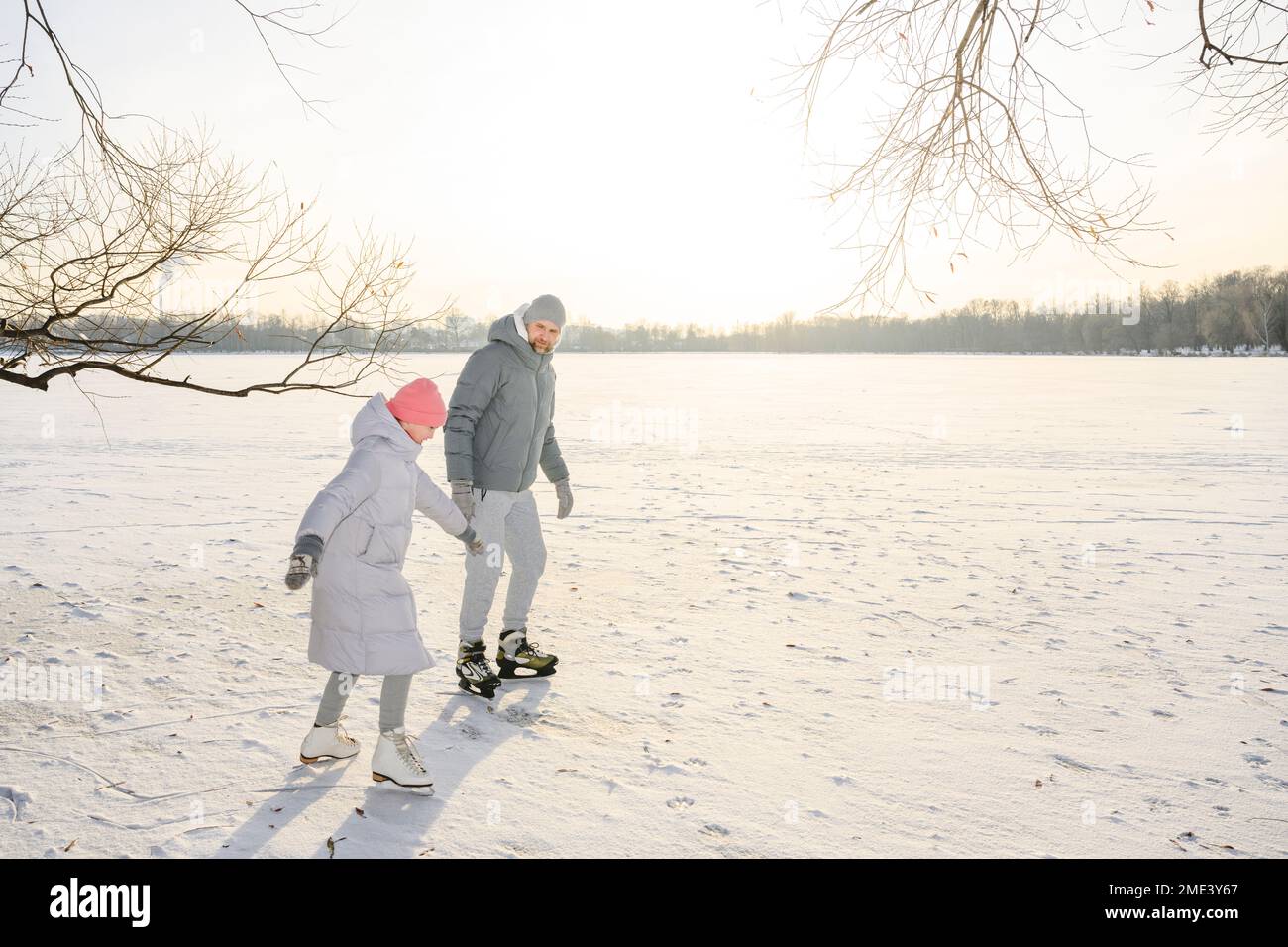 Padre e figlia che in inverno pattinano sul lago ghiacciato Foto Stock