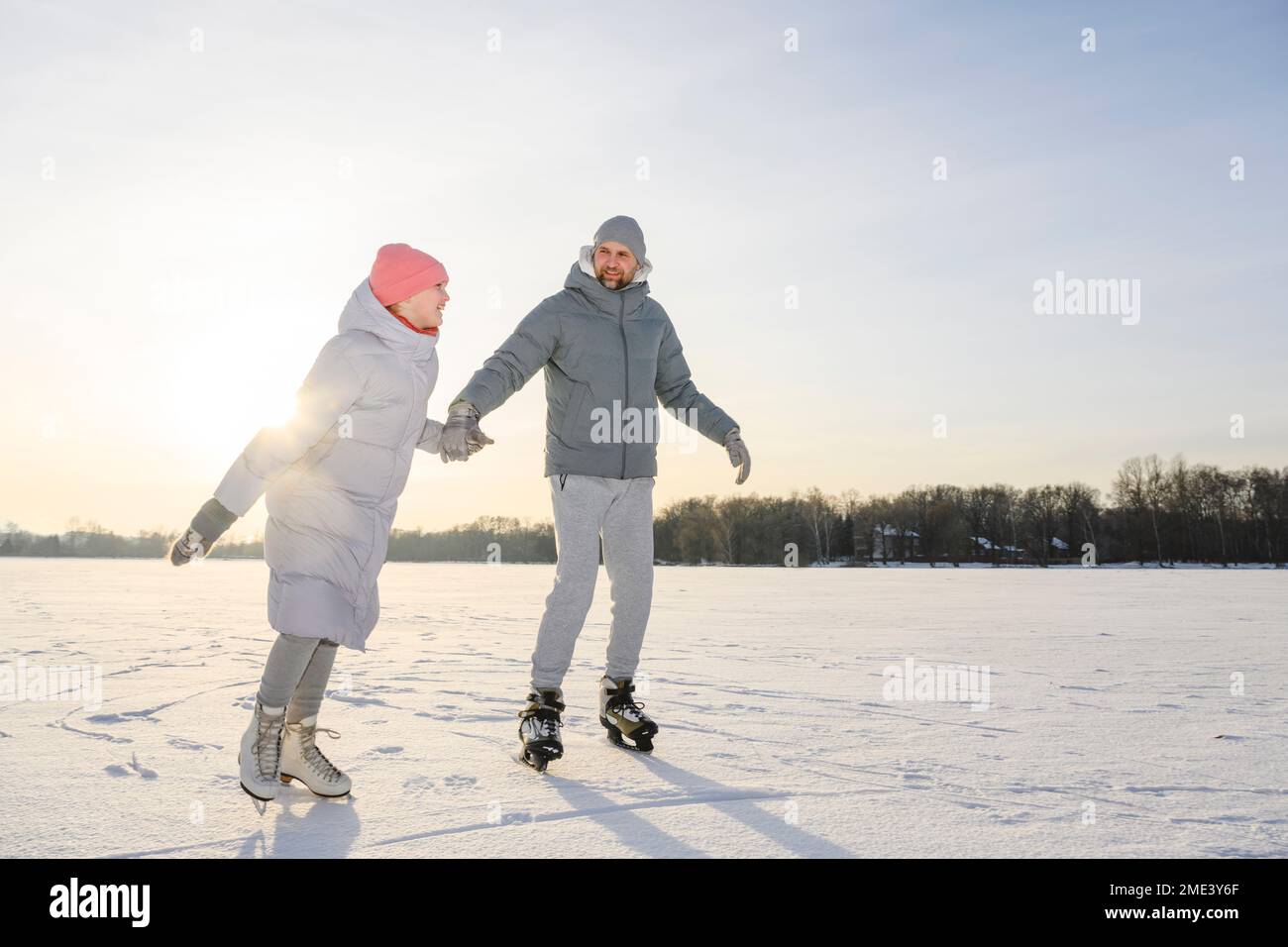 Felice figlia con padre che pratica pattinaggio sul ghiaccio sul lago d'inverno Foto Stock