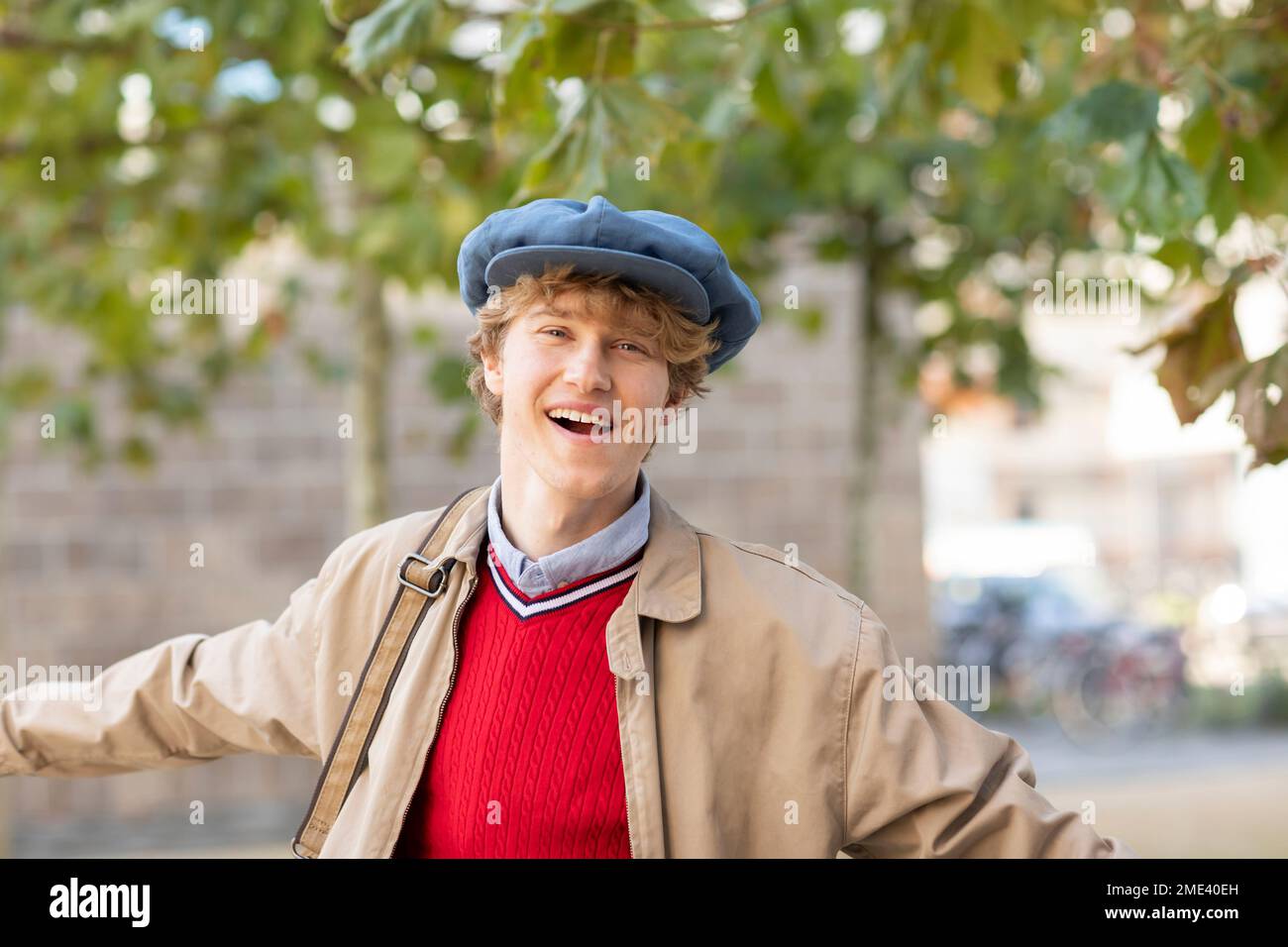 Felice giovane uomo che indossa cappello piatto e giacca Foto Stock