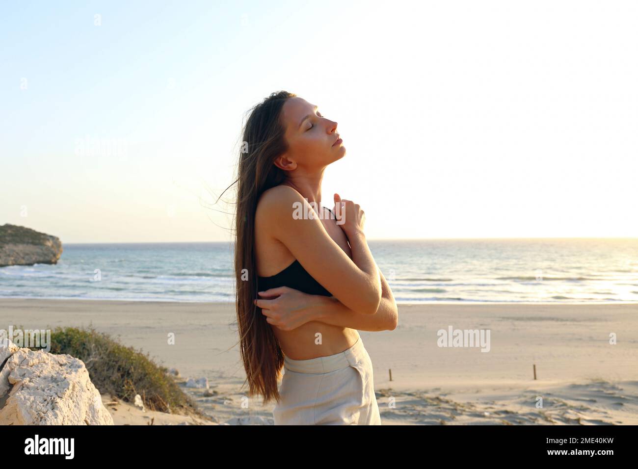 Giovane donna che si abbraccia in piedi in spiaggia, Patara, Turkiye Foto Stock