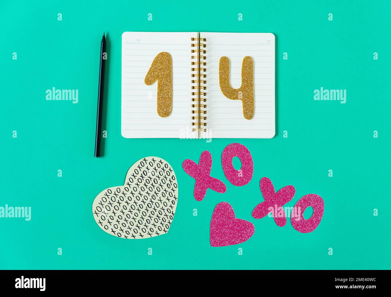 Composizione giorno di San Valentino. Sfondo turchese con taccuino, matita, numeri d'oro 14, lettere XO e cuore. Foto Stock