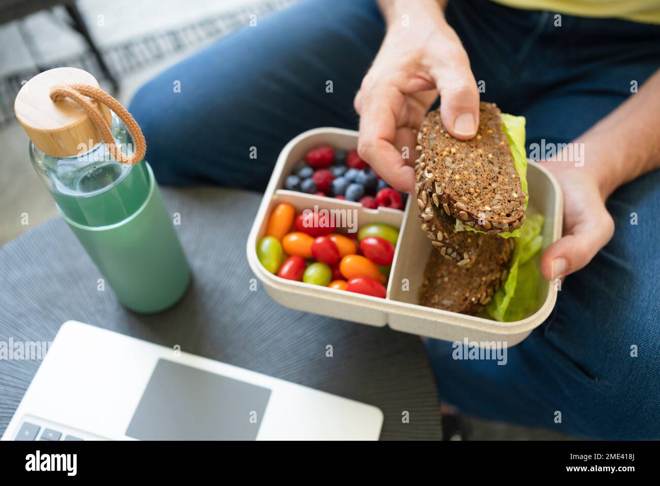 Mano di un uomo che tiene un panino sopra il pranzo al sacco Foto Stock