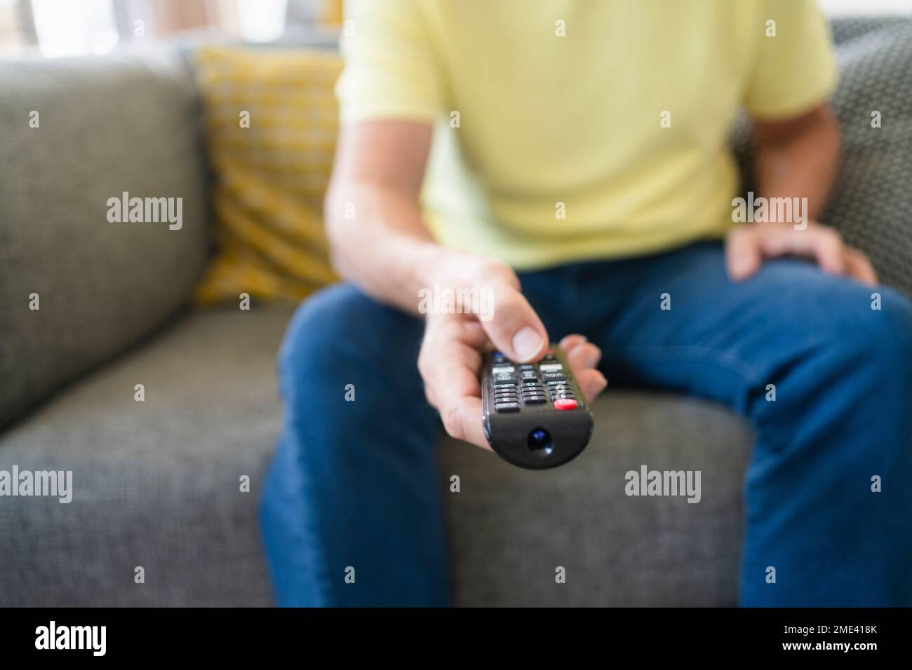 Mano di un uomo che tiene il telecomando sul divano Foto Stock