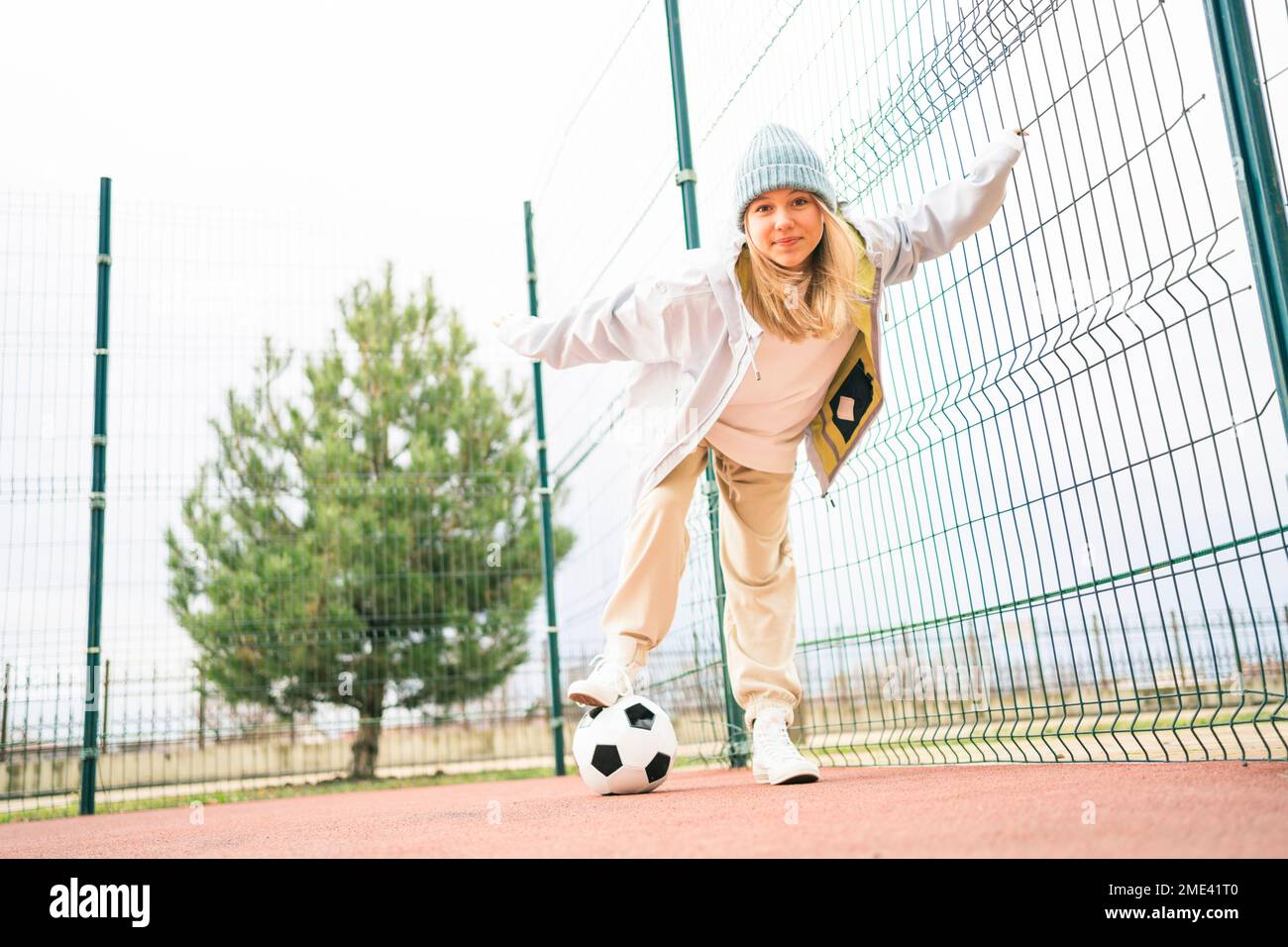 Ragazza adolescente bionda che gioca con la palla di calcio al parco giochi Foto Stock
