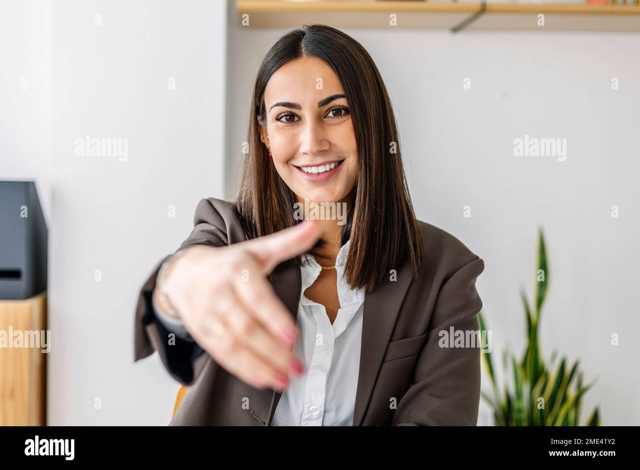 Reclutatore sorridente che fa un gesto di stretta di mano in ufficio Foto Stock