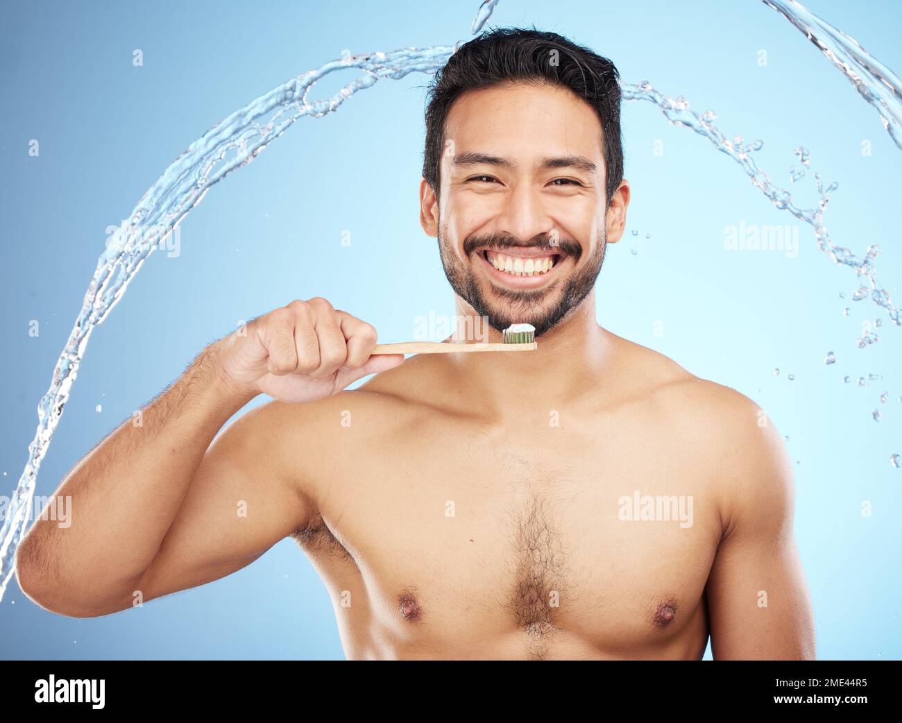 Spruzzi d'acqua, ritratti o denti per l'uomo in studio con spazzolino per denti bianchi o per la salute dentale. Faccia, legno di bambù o persona felice Foto Stock