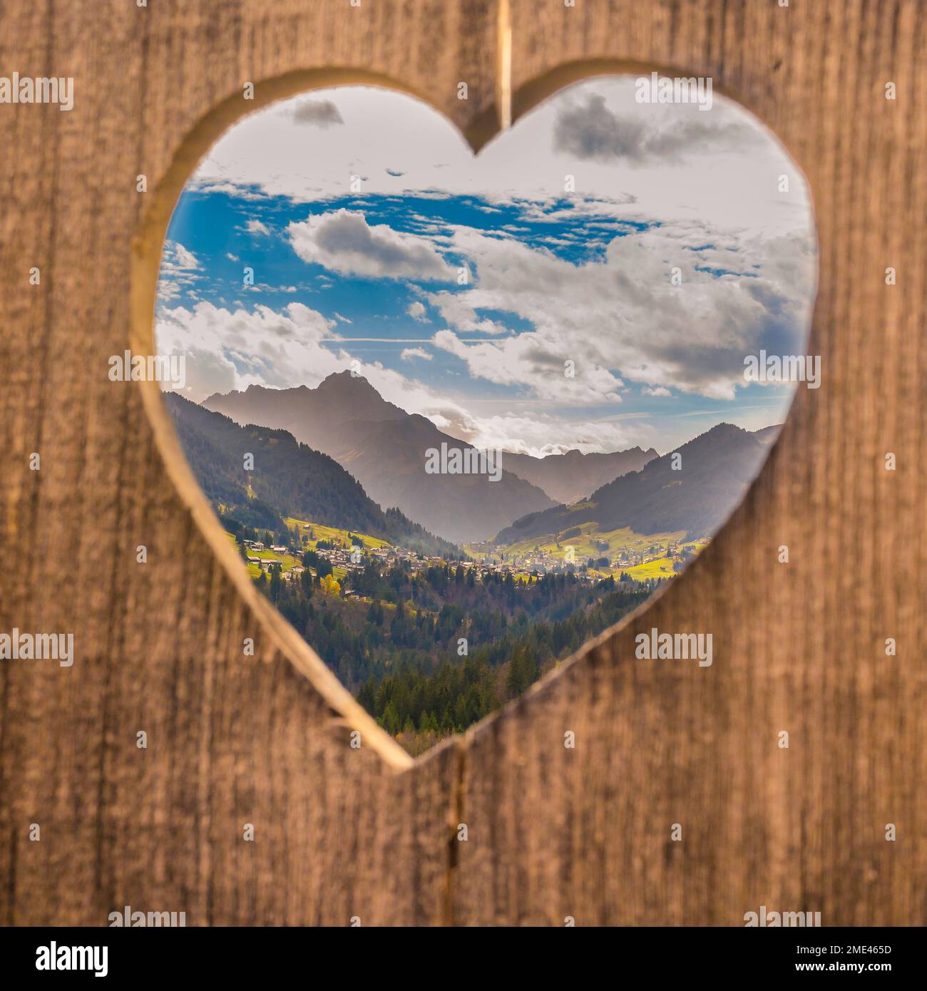 Montagne sotto il cielo visto attraverso la forma di cuore di legno Foto Stock